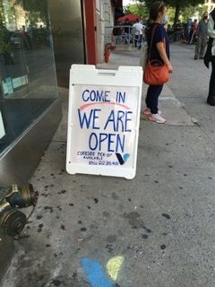 “Come in we are open” sandwich board in front of a vitamin shop