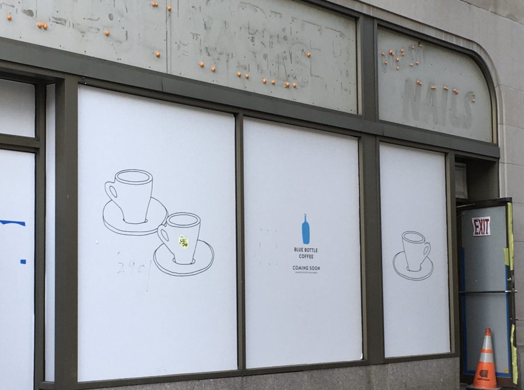 Not Yet: a papered window with Blue Bottle Coffee logo “coming soon”